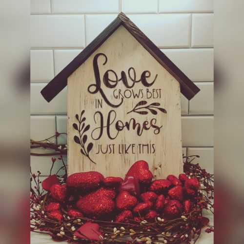 White wooden distressed block shaped like home. Engraved with Love grows best in Homes just like this